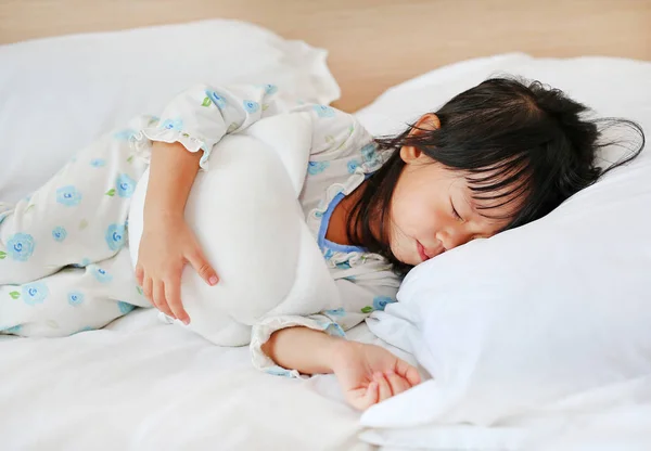 Urocza dziewczynka śpiąca w łóżku ze swoją zabawką — Zdjęcie stockowe