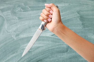 Elinde bir bıçak aşağı grev yeşil yazı tahtası arka plan üzerinde hazır el