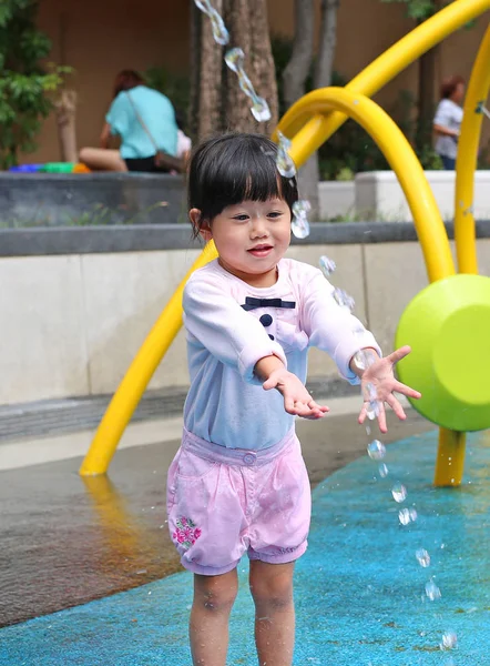 Criança menina se divertindo para brincar com a água na fonte do parque — Fotografia de Stock