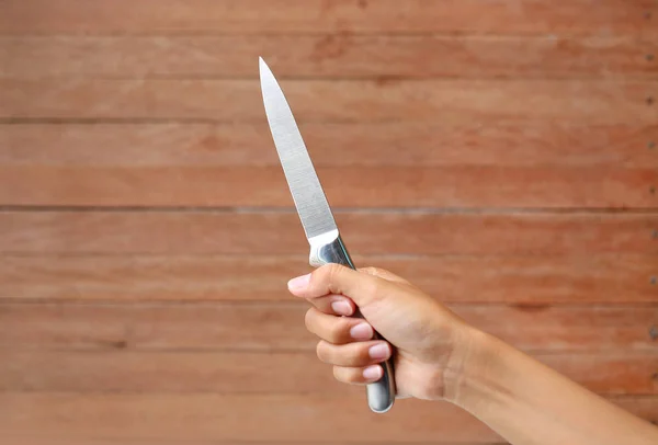 Hand hält Messer auf Holzplanke Hintergrund — Stockfoto