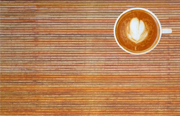 Bovenaanzicht van een kopje koffie met hart patroon in een witte beker op houten achtergrond, latte art — Stockfoto