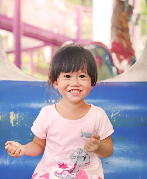 Feliz niña adorable sonriendo en un carruaje en un carrusel — Foto de Stock
