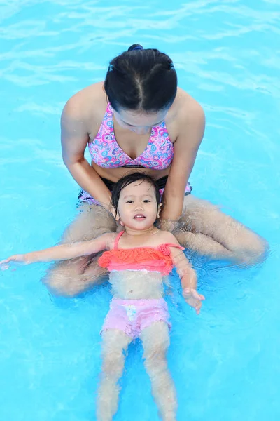 Menina bonita com a mãe brincando na piscina ao ar livre — Fotografia de Stock