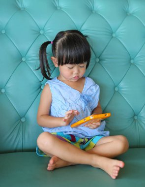 Vintage kanepede akıllı telefon kullanan Asyalı çocuk kız.