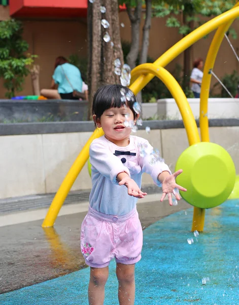 Niña divirtiéndose jugando con el agua en la fuente del parque —  Fotos de Stock