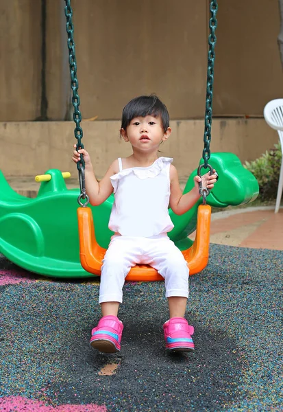 Bonito criança menina diversão em um balanço no parque infantil — Fotografia de Stock