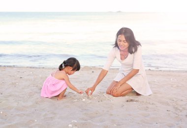 Mutlu sevgi dolu aile. Anne ve kızı çocuk kızının oynarken sahilde kum