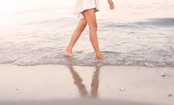 Jovem mulher de vestido branco andando sozinha na praia — Fotografia de Stock