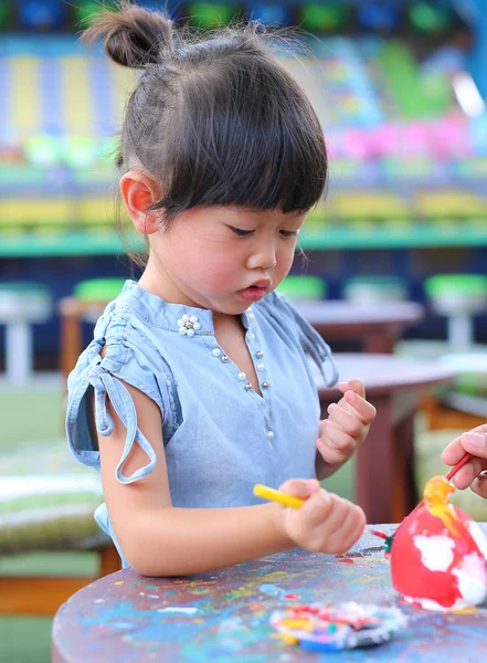 Pintura infantil, Retrato niña divirtiéndose para pintar en estuco muñeca — Foto de Stock