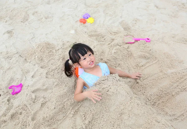 Menina bonito jogando areia na praia — Fotografia de Stock