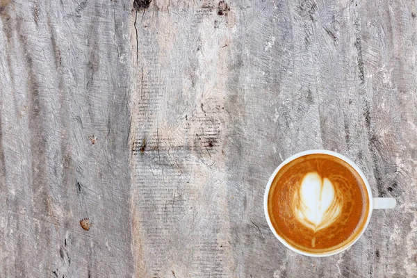 Vista superior de un café con patrón de corazón en una taza blanca sobre fondo de madera, arte latte — Foto de Stock