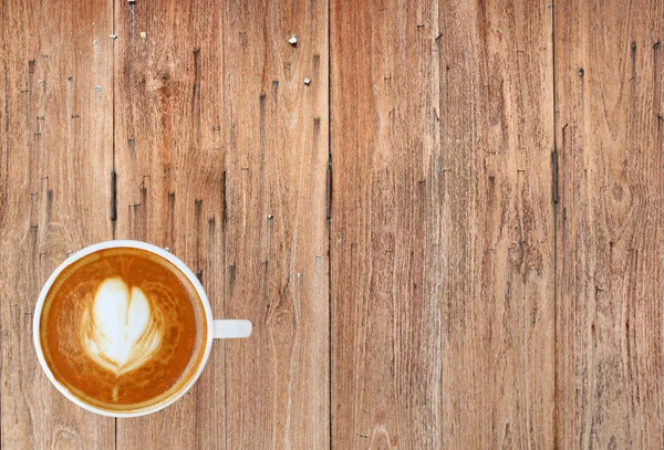 Vue du dessus d'un café avec motif coeur dans une tasse blanche sur fond de planche de bois, latte art — Photo