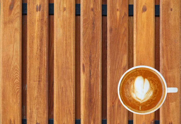 Bovenaanzicht van een kopje koffie met hart patroon in een witte beker op houten plank achtergrond, latte art — Stockfoto