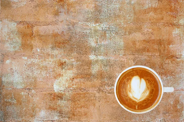 Vue du dessus d'un café avec motif coeur dans une tasse blanche sur fond de ciment rouille, latte art — Photo