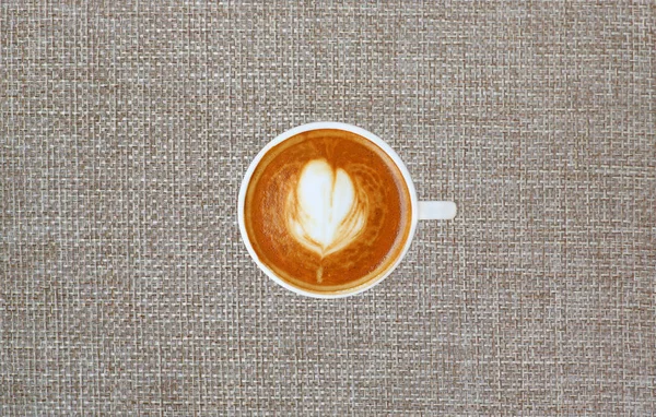 Kalp desenli beyaz bir fincan kahve üstten görünüm çuval arka planda, latte sanat — Stok fotoğraf