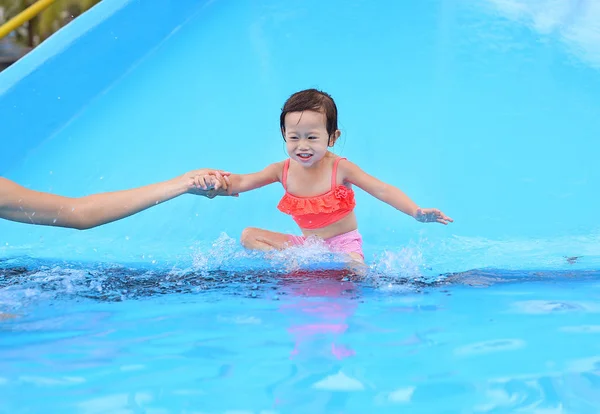 漂亮的小女孩与她的母亲在户外游泳池滑动 — 图库照片
