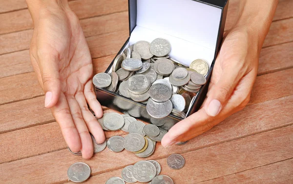 International coins full in a black square box and hands on wood plank background