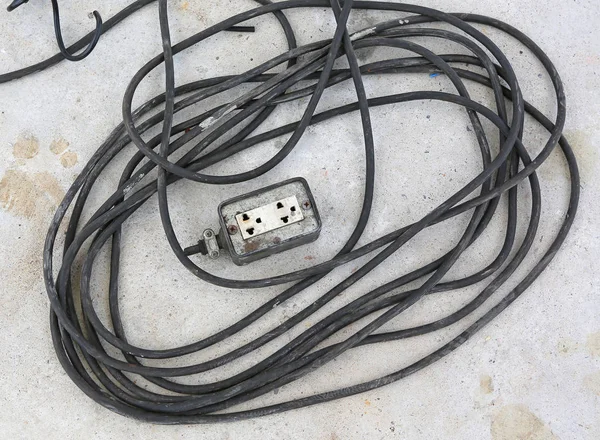 Old and damaged electrical wire on cement ground