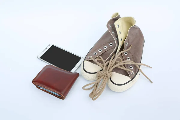 Paar nieuwe bruine sneakers met slimme telefoon en portemonnee op witte achtergrond — Stockfoto