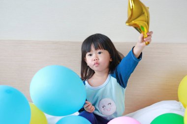 Sevimli küçük Asya kız yatakta balon ile oynamak.