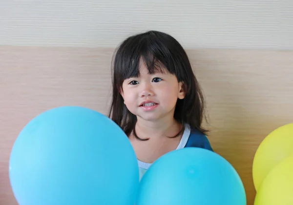 Χαριτωμένο μικρό ασιατικό κορίτσι παίζοντας στο κρεβάτι με μπαλόνι. — Φωτογραφία Αρχείου