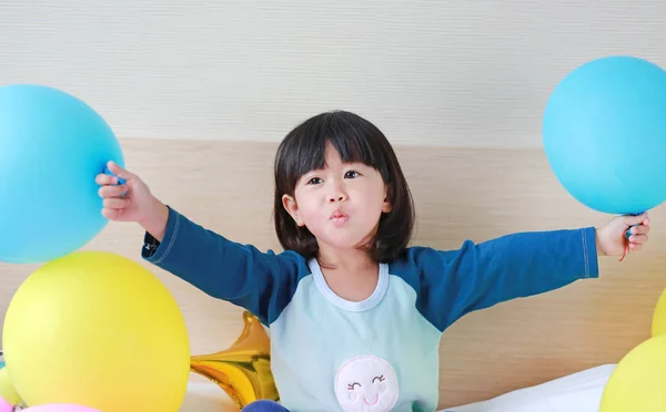 Lindo poco asiático chica jugando en cama con globo . — Foto de Stock