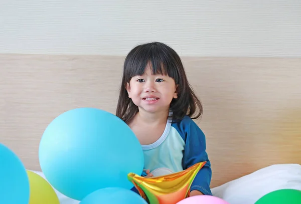 Lindo poco asiático chica jugando en cama con globo . — Foto de Stock