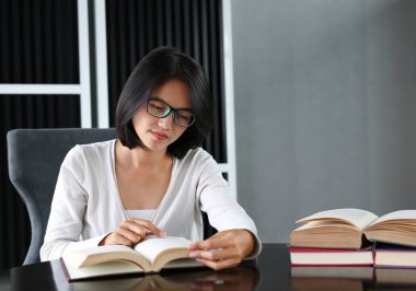 Asyalı öğrenci okuma kitabı kütüphanede