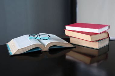 Açık kitap, ciltli kitap ve ahşap masa gözlük. Eğitim arka plan.