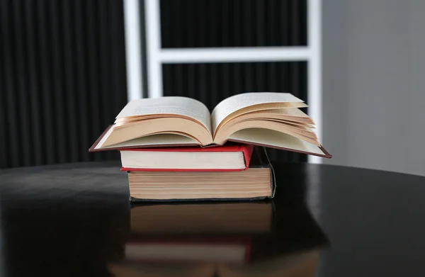 Ανοιχτό βιβλίο και στοίβα από βιβλία hardcover στο ξύλινο τραπέζι. — Φωτογραφία Αρχείου