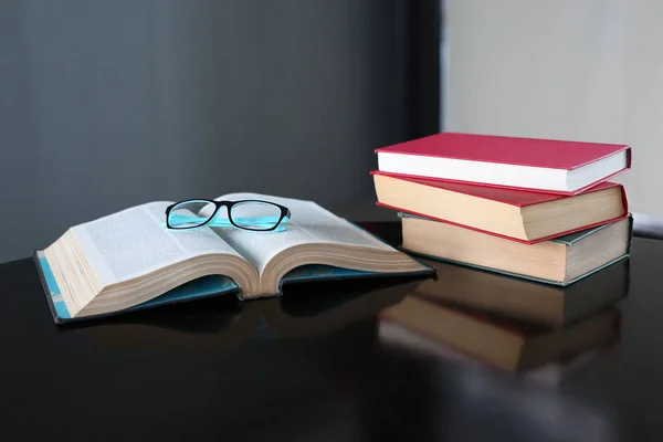 Livro aberto, livros de capa dura e óculos em mesa de madeira. Fundo de educação . — Fotografia de Stock