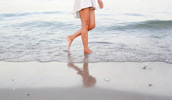 Mujer joven en vestido blanco caminando sola en la playa — Foto de Stock