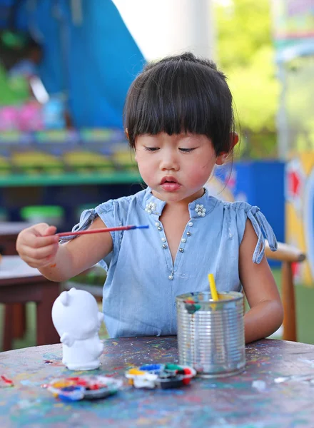 Peinture d'enfant, Portrait petite fille s'amusant à peindre sur poupée en stuc — Photo
