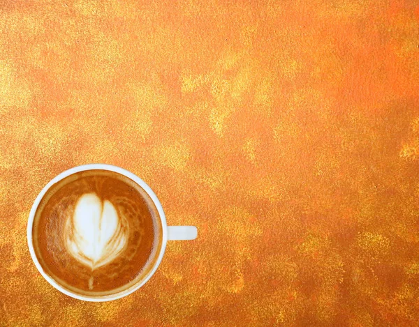 Kalp desenli beyaz bir fincan kahve üstten görünüm altın desen arka planda, Latte sanat kahve — Stok fotoğraf