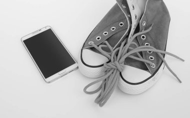 Beyaz arka plan, siyah ve beyaz tarzı akıllı telefon ile yeni ayakkabı