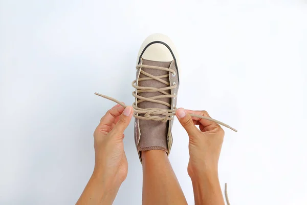 Nära upp knyta hennes skor canvas Sneakers på vit bakgrund — Stockfoto