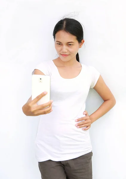 Close up asian girl taking pictures of herself through cell phone on white background — Stock Photo, Image