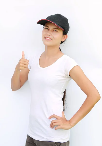 Ásia mulher desgaste t-shirt e cap mostrando polegar até no branco fundo — Fotografia de Stock
