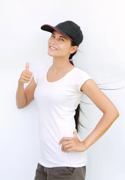 Ásia mulher desgaste t-shirt e cap mostrando polegar até no branco fundo — Fotografia de Stock