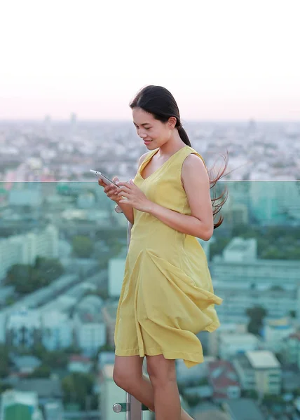 Woman using smartphone on the rooftop of the building — Stock Photo, Image