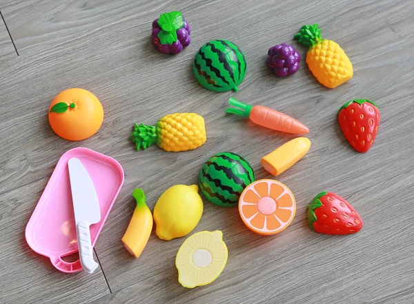 Frutos plásticos no fundo de madeira, brinquedo infantil — Fotografia de Stock