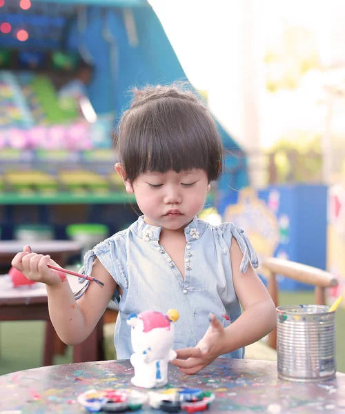 Peinture d'enfant, Portrait petite fille s'amusant à peindre sur poupée en stuc — Photo