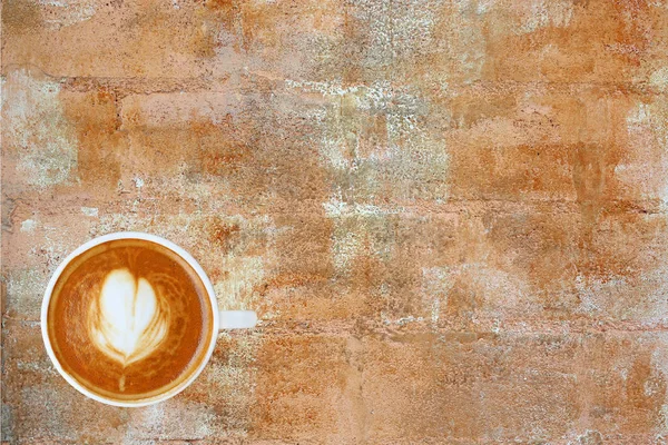 Ovanifrån en kaffe med hjärtmönster i en vit kopp på rostiga cement bakgrund, latte art — Stockfoto