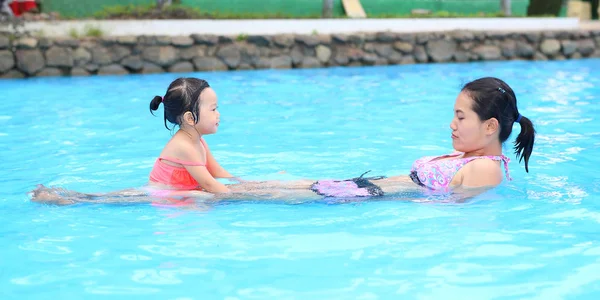 Красивая маленькая девочка с матерью в бассейне на открытом воздухе — стоковое фото