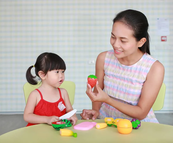 Asiatico bambino ragazza e madre giocare plastica frutta a il bambino stanza — Foto Stock