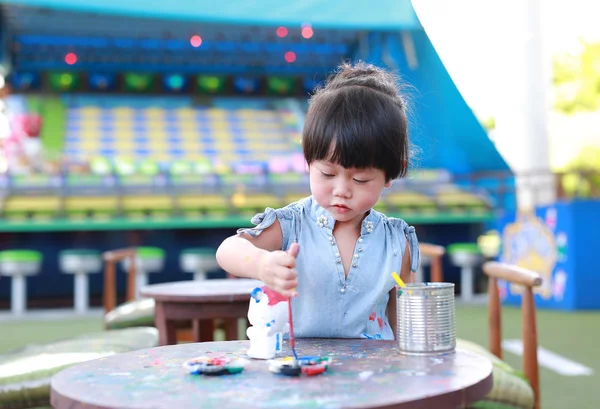 Pintura infantil, Retrato niña divirtiéndose para pintar en estuco muñeca — Foto de Stock