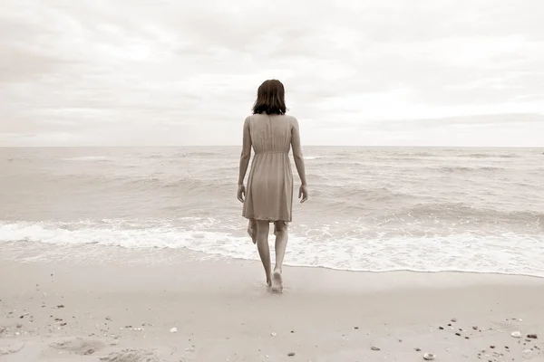 Mujer joven caminando sola en la playa, ir directamente al mar, tono vintage — Foto de Stock