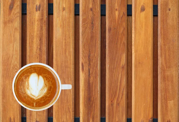 Bovenaanzicht van een kopje koffie met hart patroon in een witte beker op houten plank achtergrond, latte art — Stockfoto