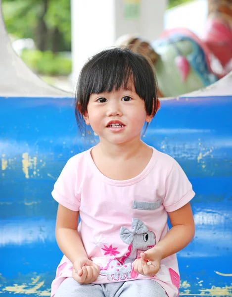 Feliz niña adorable sonriendo en un carruaje en un carrusel — Foto de Stock