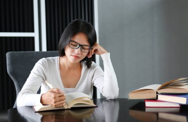 Asyalı kadın kütüphanede kitap okuma.